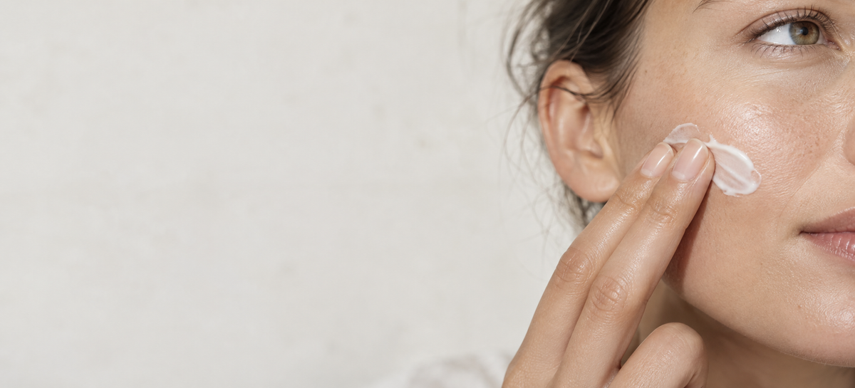 Woman gently applying moisturizer to her cheek.