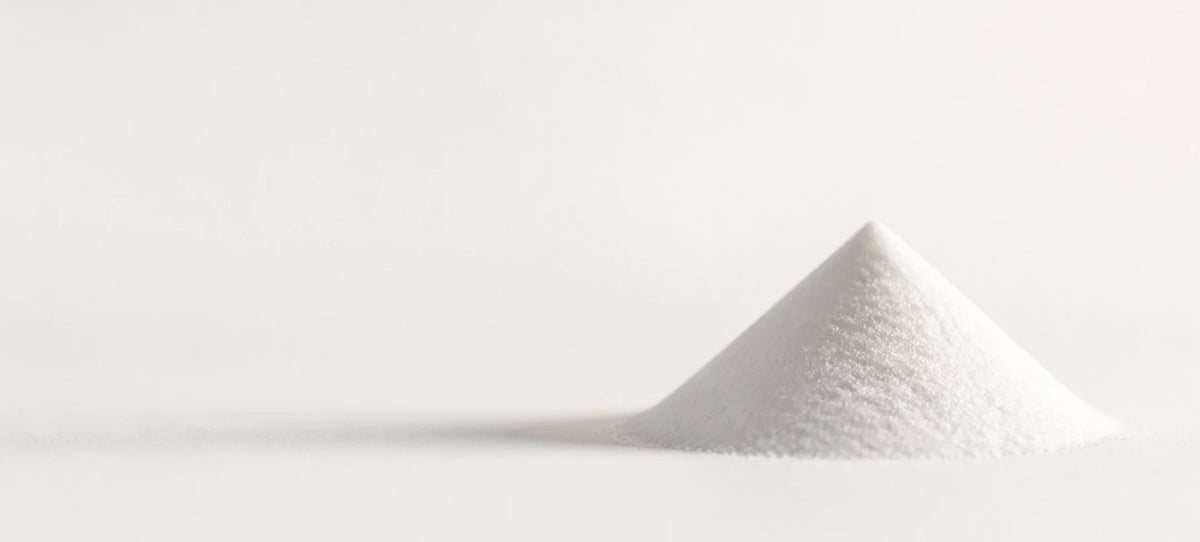 A small mound of white powder or fine granules photographed on a clean white background.