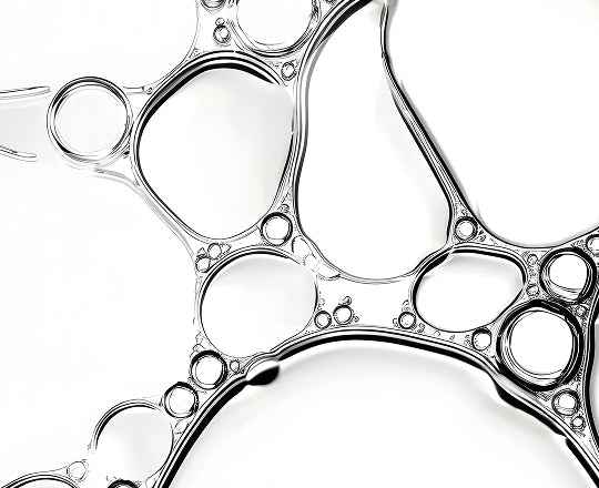 Abstract close-up of a transparent, glossy liquid or gel forming irregular circular and oval shapes against a white background.