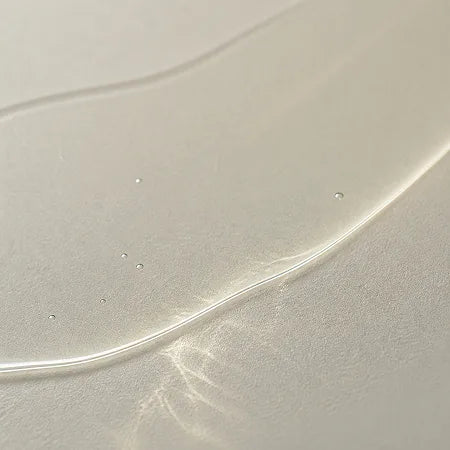 A close-up of a translucent, clear silicone or rubber band with a smooth, glossy surface and a few small air bubbles trapped within it.
